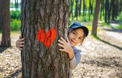 Premium Photo Portrait Of Cute Girl Embracing Tree Trunk