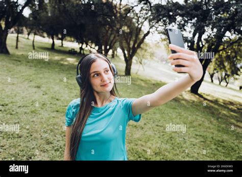 Smiling Teenage Girl Wearing A Turquoise T Shirt And Headphones Taking A Selfie With Her Mobile