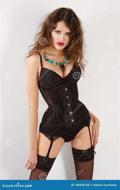 Girl In Burlesque Corset And Lingerie Posing Against Wall Stock Photo