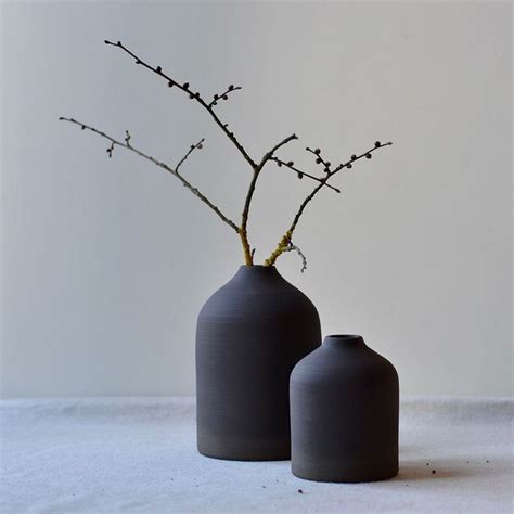 Two Gray Vases Sitting Next To Each Other On Top Of A White Tablecloth