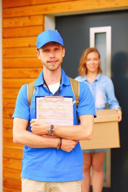 Premium Photo Smiling Delivery Man In Blue Uniform Delivering Parcel