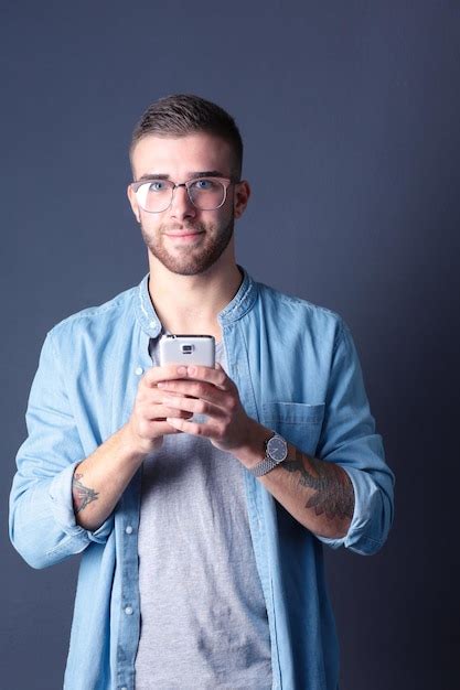 Premium Photo Smiling Young Man Holding Phone While Text Messaging