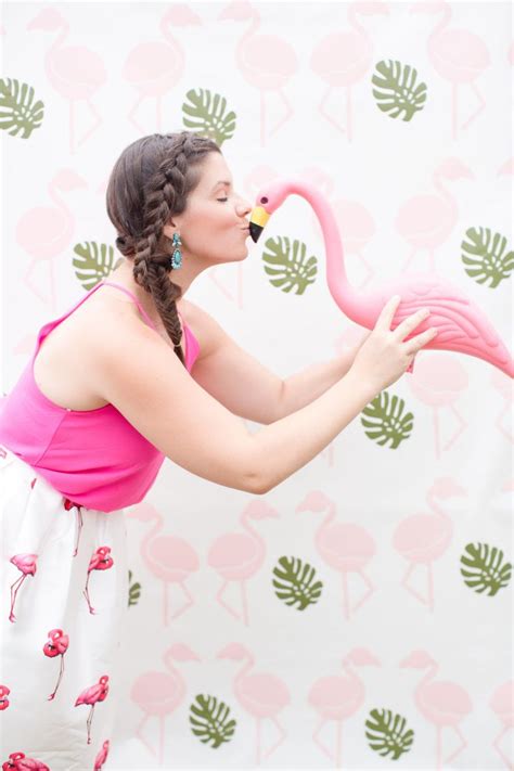 A Woman In Pink Shirt Blowing Out Flamingos On Wallpaper With Palm