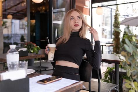 Premium Photo Brooding Blonde Woman Sits In Coffee Shop With Cup Of Cappuccino Coffee Latte
