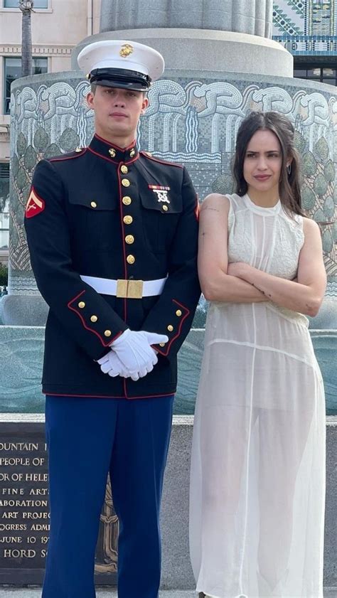 A Man In Uniform Standing Next To A Woman