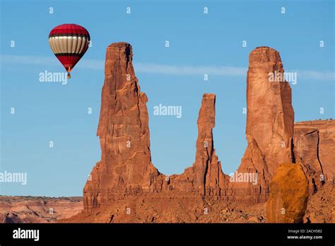 A Hot Air Balloon Flying By The Three Sisters In The Monument Valley