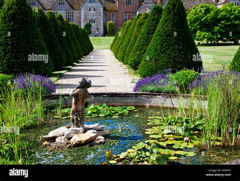 Ornamental Pondstatue And Topiary In The English Country Garden Of