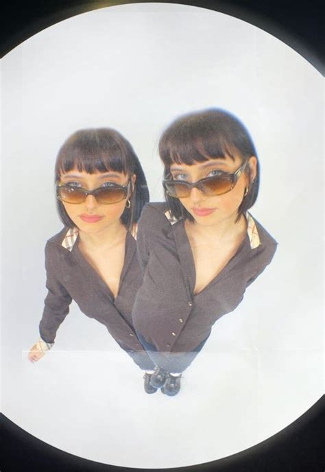 Two Women Wearing Sunglasses Are Standing In Front Of A White Circle