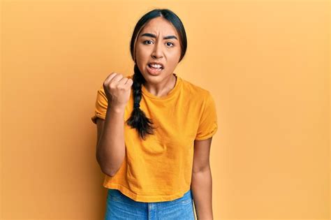 Joven mujer latina con ropa informal enojada y loca levantando el puño