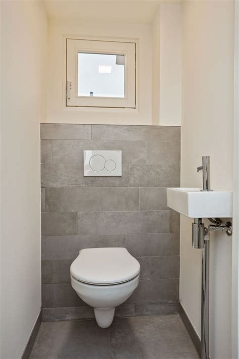 A White Toilet Sitting In A Bathroom Next To A Sink Under A Window With