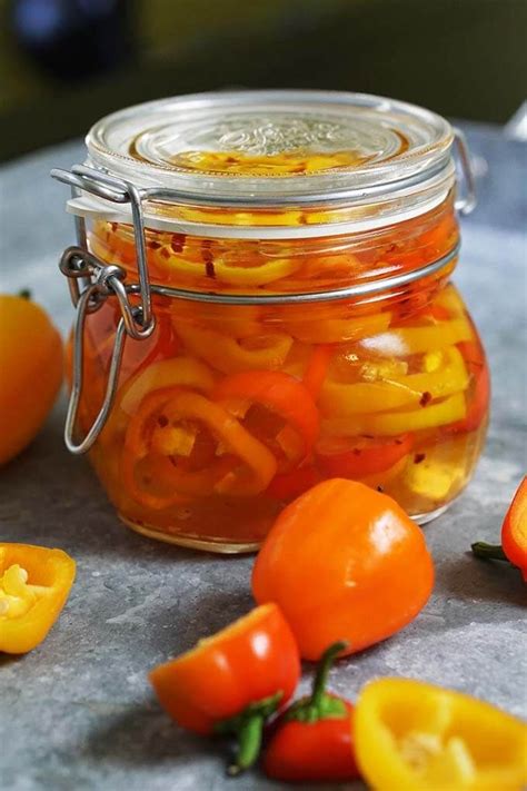 A Glass Jar Filled With Sliced Bell Peppers On Top Of A Counter Next To