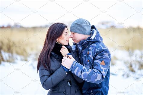 Beautiful young couple hugging in a park in winter snow-covered field ...