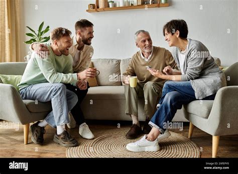 A Gay Couple Sits On A Couch With Parents Laughing And Enjoying Each Others Company Stock Photo
