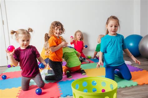 Niños felices lanzando pelotas en una canasta de plástico Foto Premium