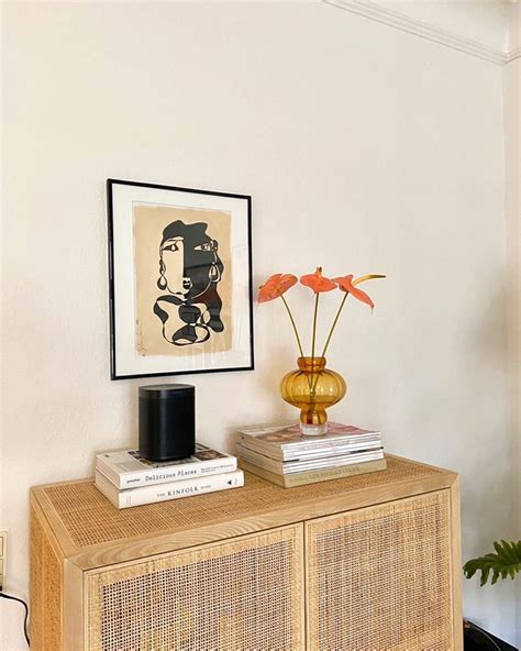 A Wooden Cabinet With Two Books On Top Of It Next To A Painting And Vase