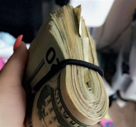 A Person Holding A Bundle Of Money In Their Hand