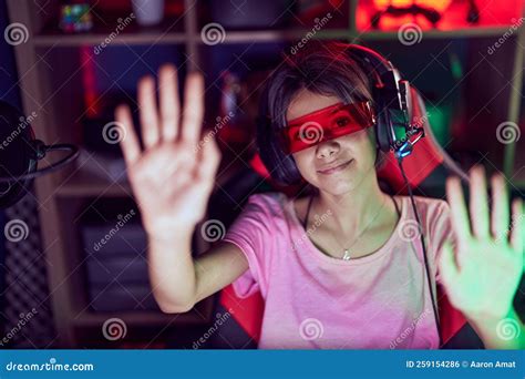 Adorable Hispanic Girl Streamer Playing Video Game Using Virtual Reality Glasses At Gaming Room