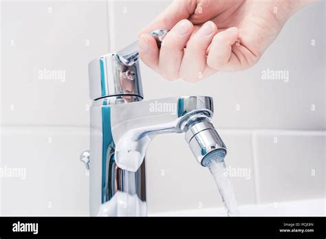 Female Hand On The Handle Of A Chrome Faucet With Running Water Stock