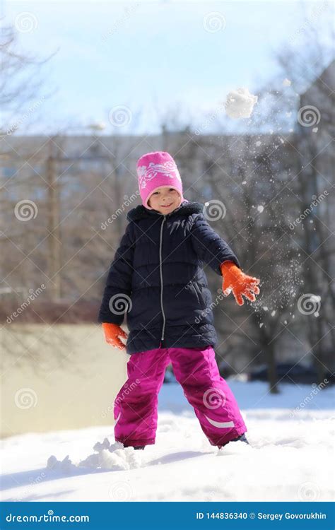 Jeux D Hiver Une Petite Fille Jette Une Boule De Neige Photo Stock