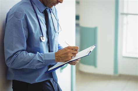 Premium Photo Mid Section Of Doctor Writing On Clipboard