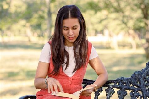 Joven Latina Leyendo Un Libro Sentado En Una Banca Del Parque