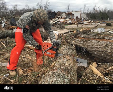 National Guard Soldiers Cut Down Fallen Trees To And Clear Debris To Open A Blocked Road After A