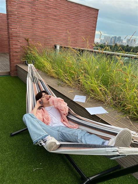 A Man Laying In A Hammock On Top Of A Roof Talking On A Cell Phone