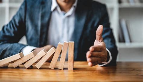 Premium Photo Businessman Halts Falling Domino With Hand Symbolic Of