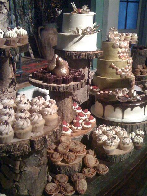 A Table Topped With Lots Of Cakes And Cupcakes On Top Of Wooden Slices