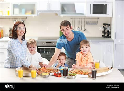 Familia Feliz comiendo pizza en la cocina juntos Fotografía de stock