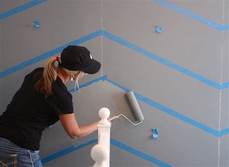 A Woman Painting A Wall With Blue Stripes On The Walls And White Trimmings