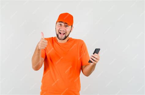 Free Photo Delivery Man In Orange T Shirt Cap Holding Mobile Phone