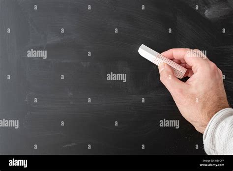 Hand Holding Stick Of Chalk Against Chalkboard Stock Photo Alamy