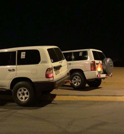 Two White Suvs Parked In A Nighttime Parking Lot