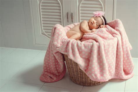 Beautiful Newborn Baby Sleeping On A Pink Blanket In A Wicker Basket