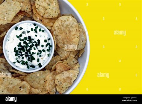 Snack Food Of Potato Crisps With Sour Cream And Chive Dip With Copy Space Flat Lay On Yellow