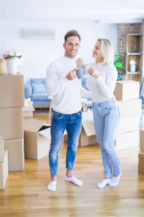 Young Beautiful Couple Standing Drinking Cup Of Coffee At New Home