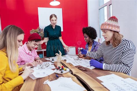 Four Creative Students Of Fashion Department Listening To Teacher Stock