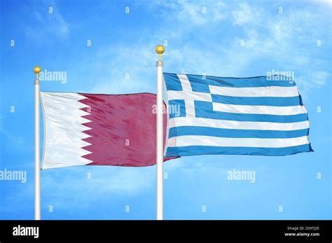 Qatar And Greece Two Flags On Flagpoles And Blue Cloudy Sky Stock Photo