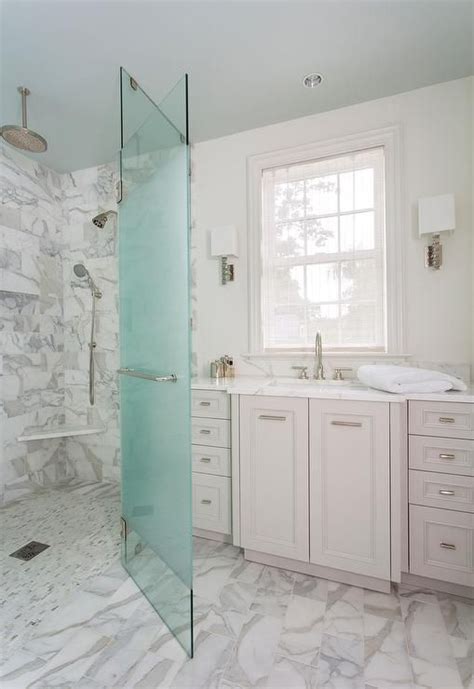 A Bathroom With Marble Flooring And White Walls Along With A Glass