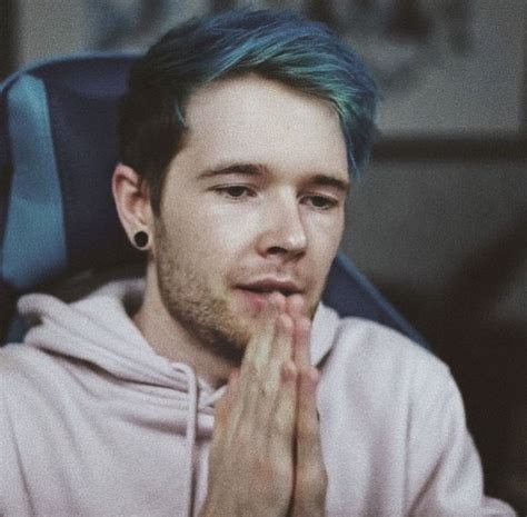 A Man With Blue Hair And Piercings Sitting In A Chair While Holding His