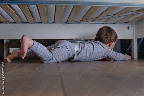 Toddler baby crawls and hides under the bed. Child climbed under the ...