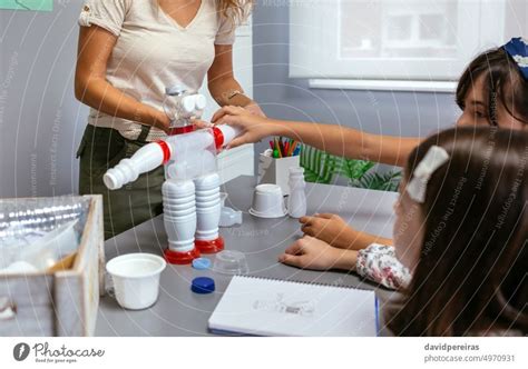 Teacher Helping To Girl Make Recycled Toy Robot With Hot Melt Glue Gun A Royalty Free Stock