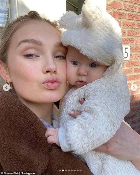 A Woman Holding A Baby In Her Arms And Wearing A White Teddy Bear Hat