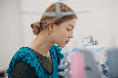 Costurera hermosa joven cose en la máquina de coser en la fábrica