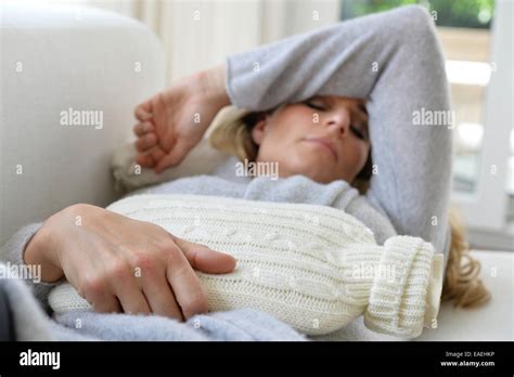 A Woman With A Hot Water Bottle Is Lying On The Sofa Stock Photo Alamy
