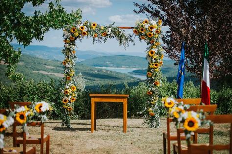 An Outdoor Ceremony Set Up With Sunflowers And Greenery On The Aisle