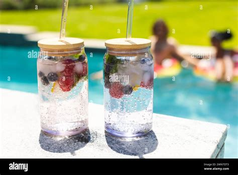 Two Refreshing Fruit Infused Water Jars With Straws Sit By A Pool Stock