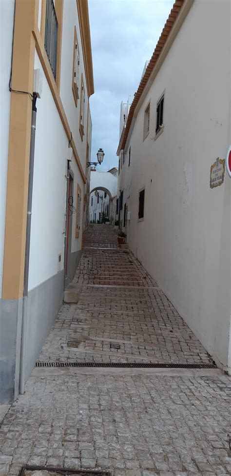 An Alley Way With White Buildings And Cobblestone Pavement In The