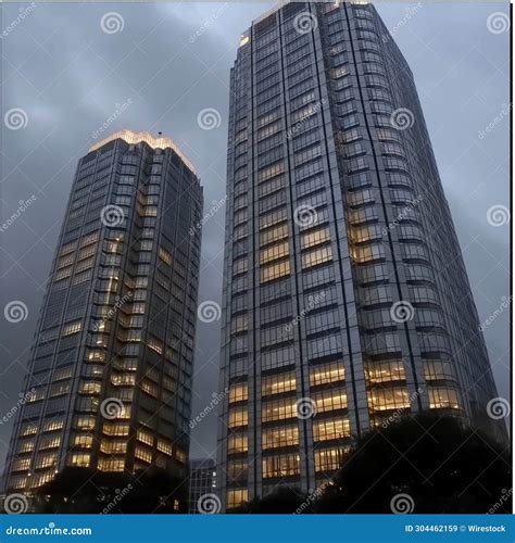 Two Tall Skyscrapers With Lights Reflected On The Glass Stock